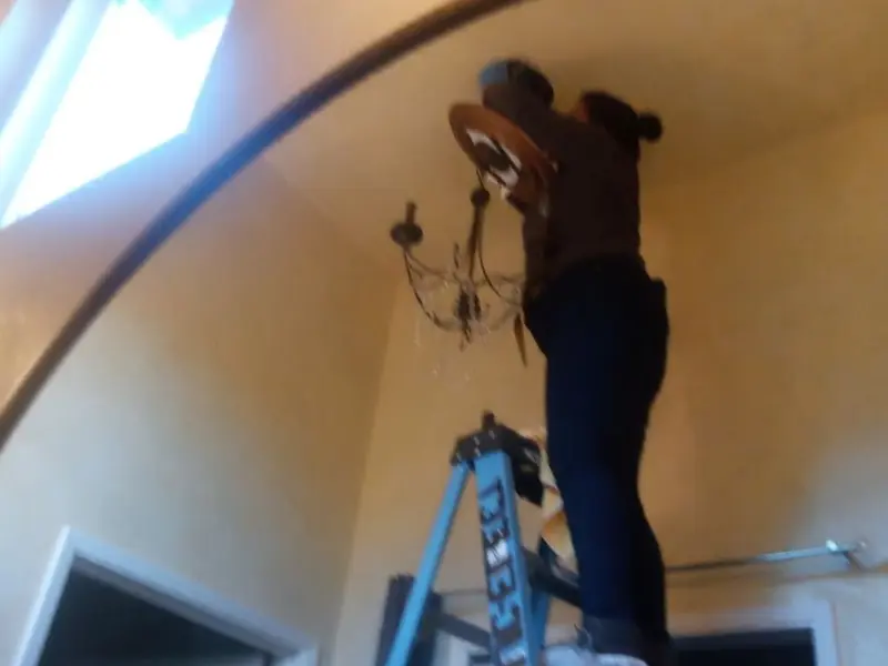 Electrician installing a chandelier in a Trumann residence